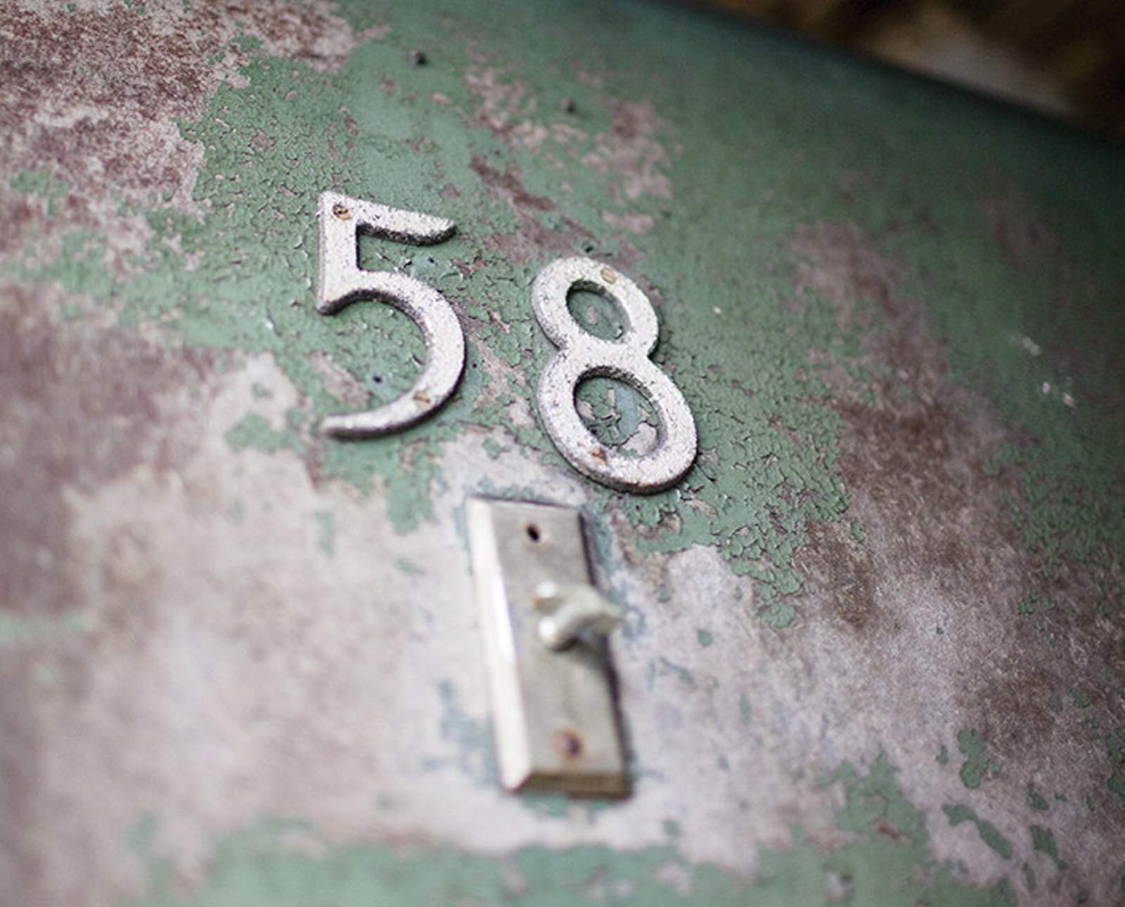 The number 58 on a faded green-painted surface with door bell below.