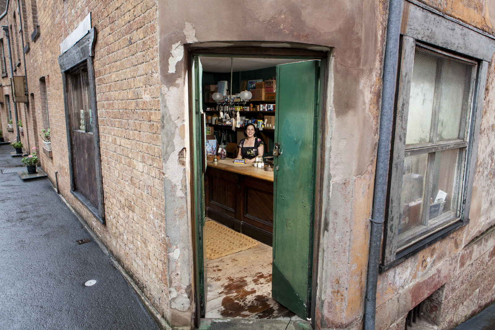 View through front door showing curator Anna Cossu behind the counter of the corner shop, 64 Gloucester Street, Susannah Place Museum