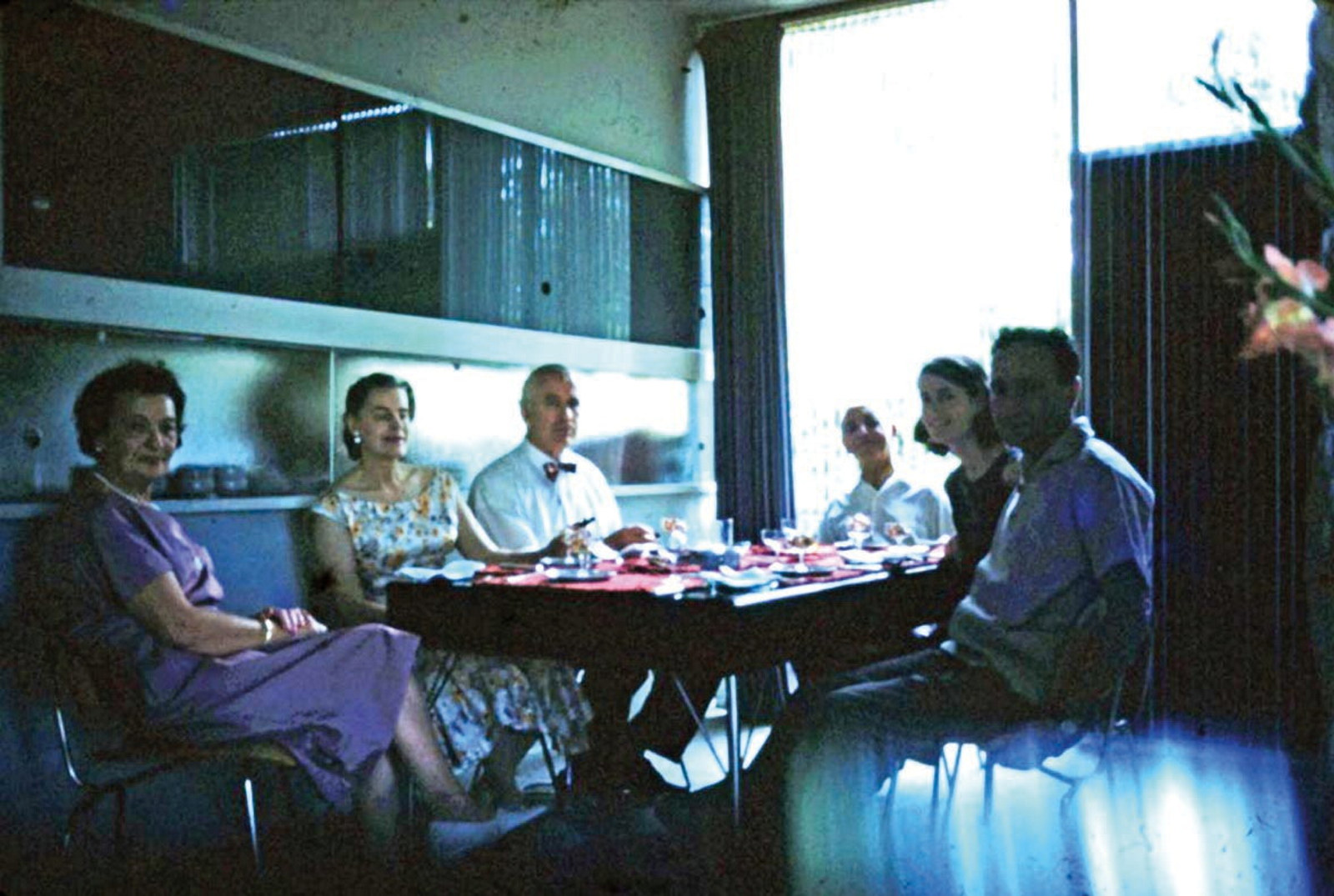 Group seated around dining table in front of kitchen area.