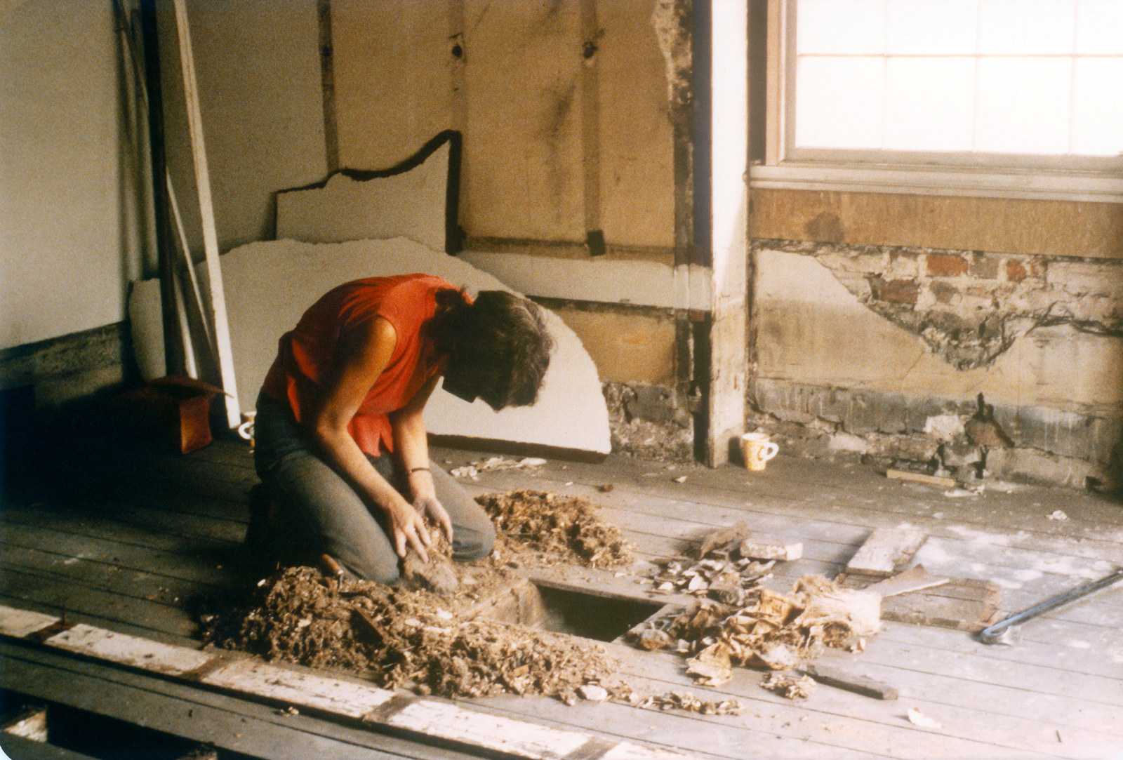 Archaeologist with dust mask removing decades of accumulated deposit from beneath the floorboards, Hyde Park Barracks, 1980.