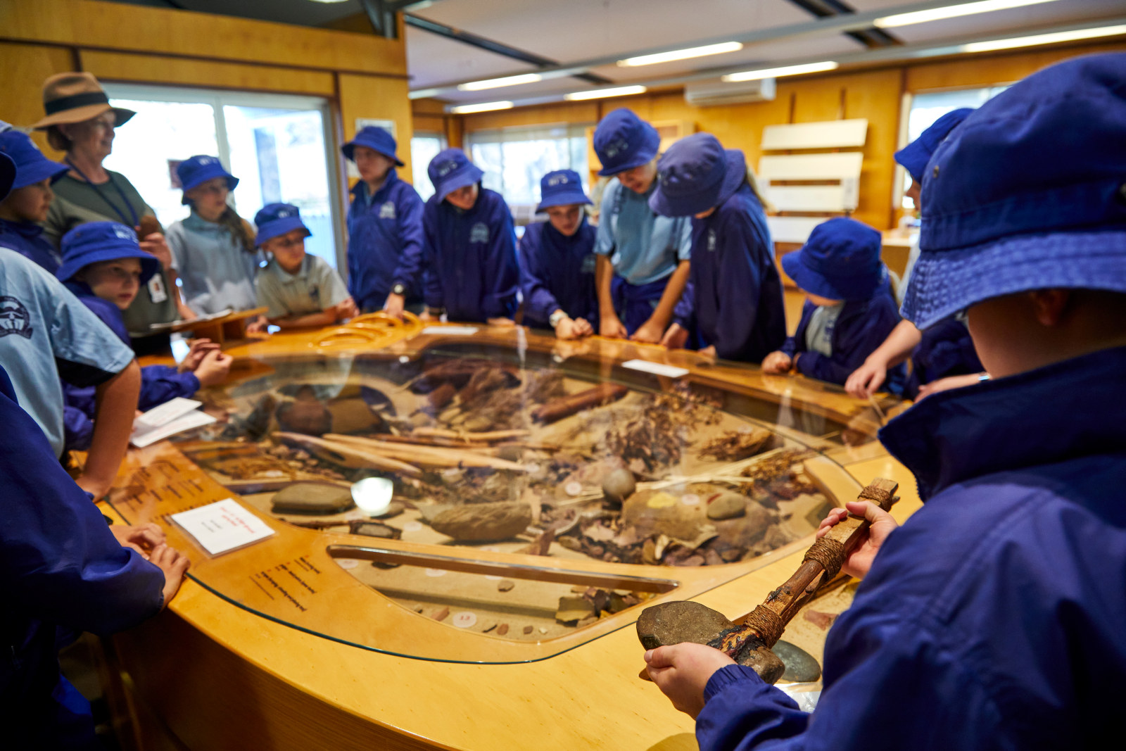 Students gather around the Darug object case in the Visitor Centre, examining artefacts and displays from the local indigenous community.