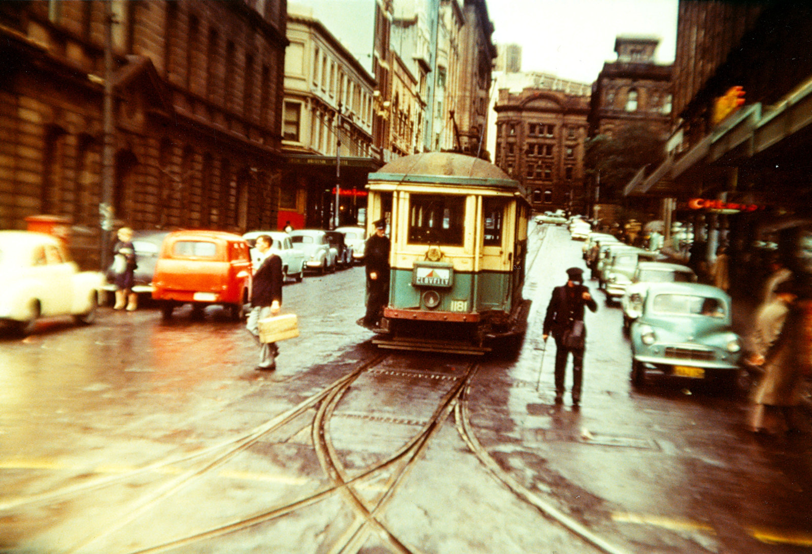 Colourful image of a green and yellow tram making its way down Sydney city street.