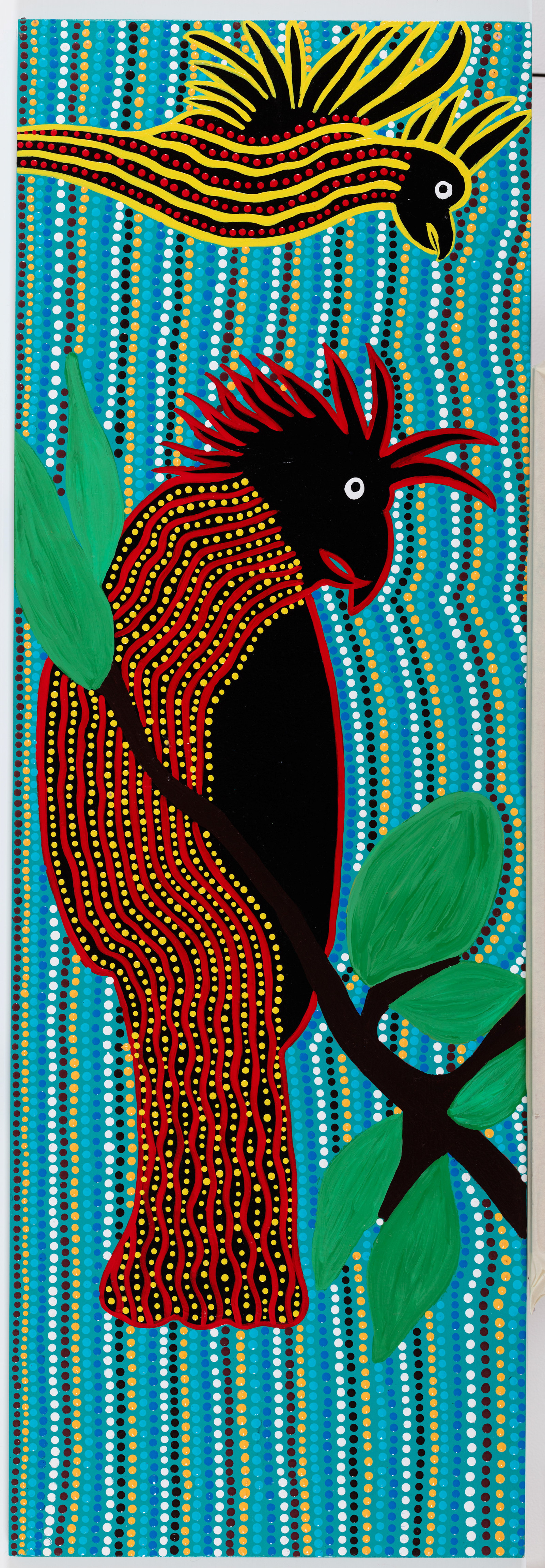 The black cockatoo, Lorraine Brown and Narelle Thomas, with design work by Allison Day, 2022, acrylic on plywood board, 122.5cm x 41cm
The Dreaming Stories tell us of their encounter with the Rainbow of the Dreaming. All the birds wanted to be beautiful colours like the flowers – so they asked the flowers where they got their colours. The flowers told them of the rainbow and how it gave them their colours – so the birds waited for the day when the rainbow would return. When it came they dipped in and out of the rainbow’s beautiful colours to become bright and beautiful. But the crows and cockatoos missed out and remain the colours they are today. One of our beautiful birds – we hear their calls after the storms or in the dry weather.