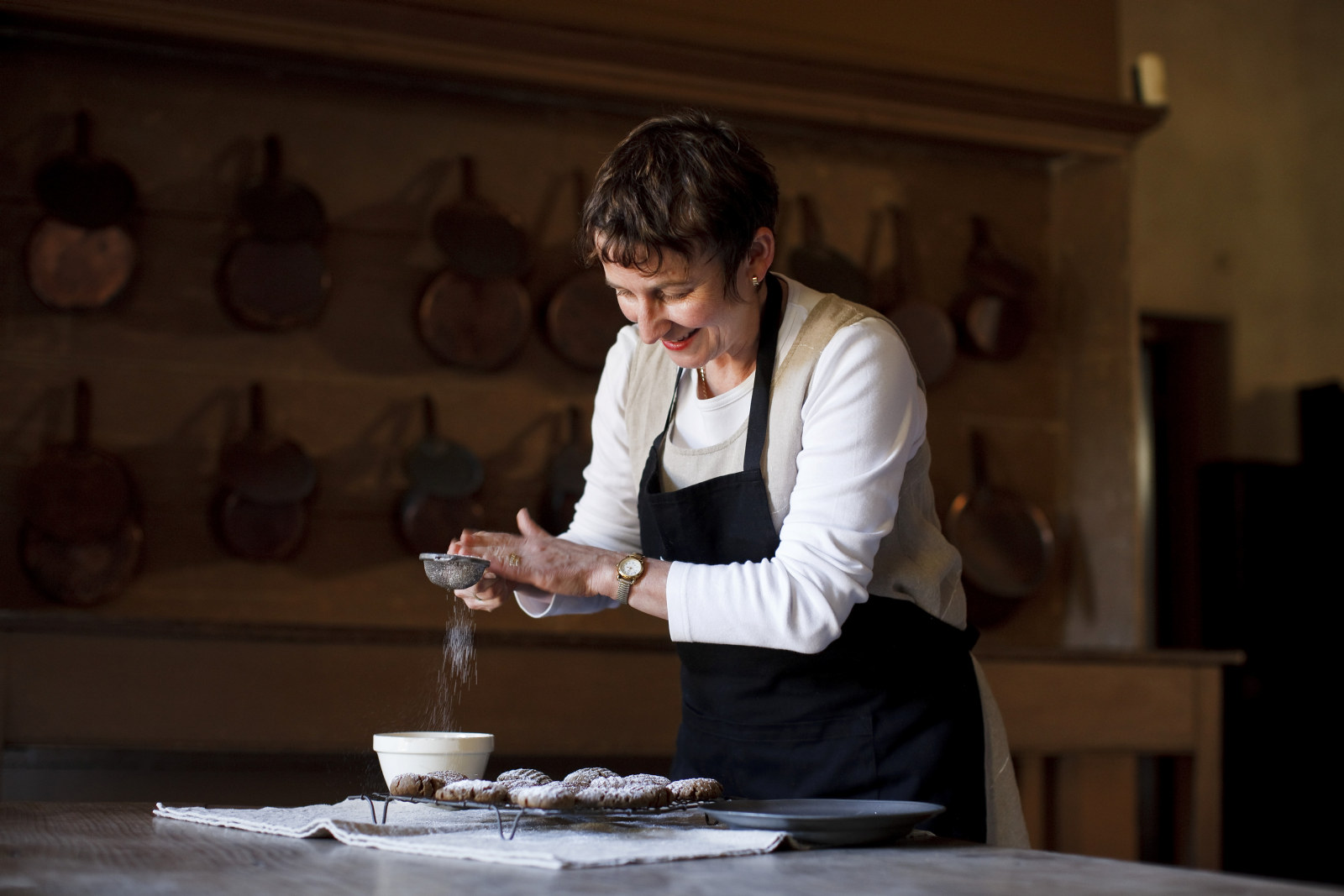 Jacqui Newling making ginger nut biscuits, sifting icing sugar onto biscuits, provenanced handwritten recipe, Rouse Hill House and Farm, in kitchen at Vaucluse House
